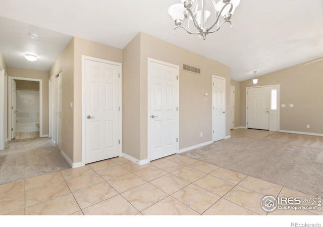 interior space with light tile patterned floors, visible vents, baseboards, lofted ceiling, and light colored carpet