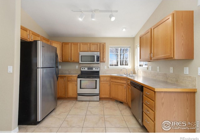 kitchen featuring light tile patterned floors, lofted ceiling, a sink, light countertops, and appliances with stainless steel finishes