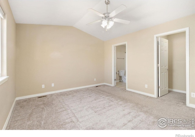 unfurnished bedroom featuring visible vents, connected bathroom, carpet flooring, baseboards, and vaulted ceiling