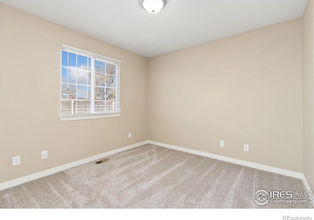 carpeted empty room featuring visible vents and baseboards