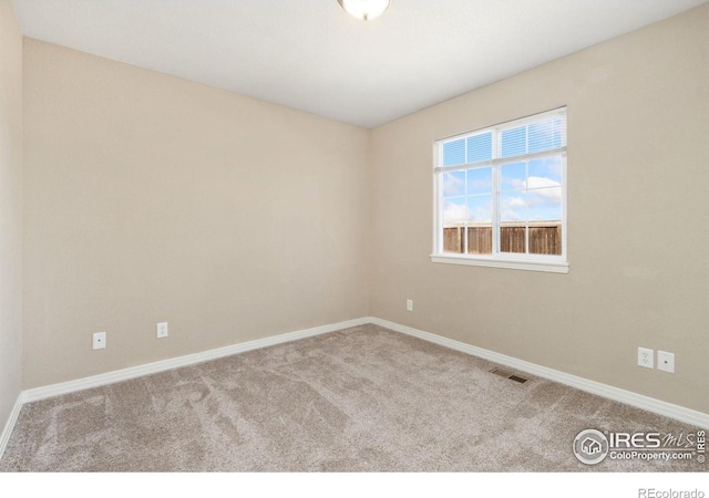 carpeted spare room featuring visible vents and baseboards