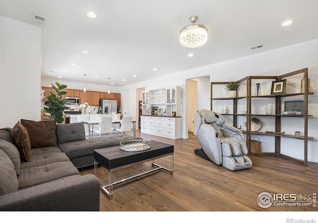 living room with visible vents, recessed lighting, and wood finished floors