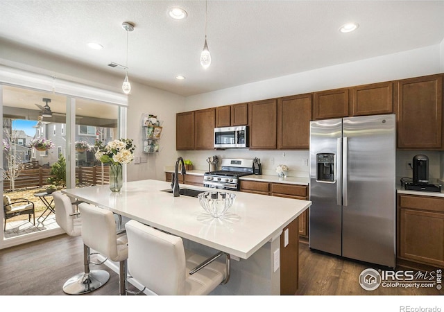 kitchen with light countertops, dark wood-style flooring, hanging light fixtures, stainless steel appliances, and a sink