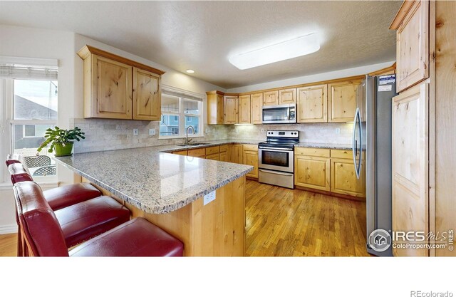 1386 Plains Ct, Eaton, CO 80615 - kitchen with light wood finished floors, a peninsula, stainless steel appliances, and a sink