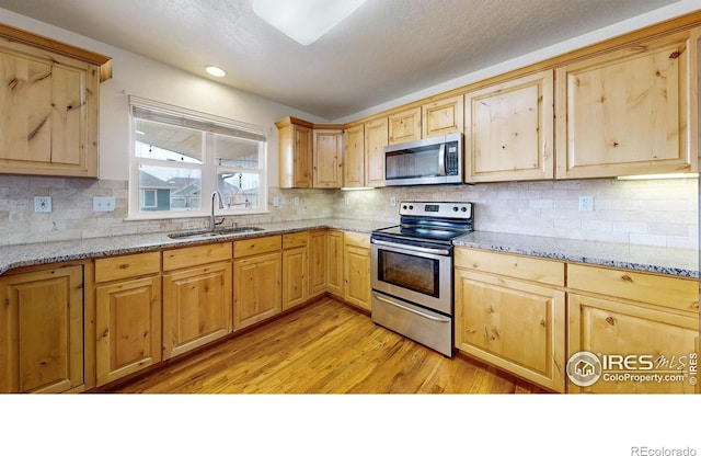 1386 Plains Ct, Eaton, CO 80615 - kitchen with light wood-style flooring, light brown cabinets, a sink, light stone counters, and stainless steel appliances