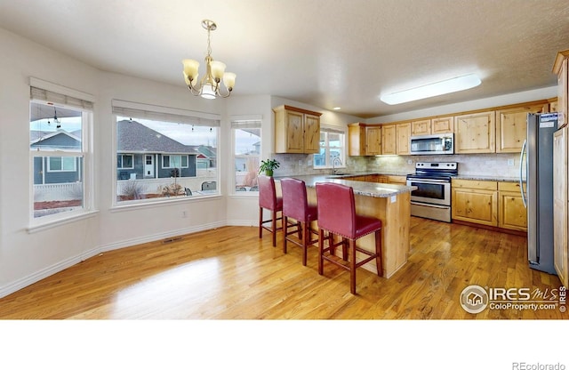 1386 Plains Ct, Eaton, CO 80615 - kitchen featuring a breakfast bar area, light wood-style flooring, a sink, stainless steel appliances, and backsplash