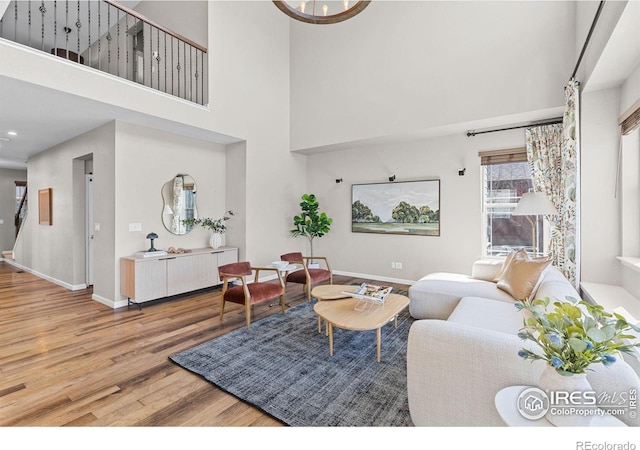 living area with a towering ceiling, baseboards, and wood finished floors