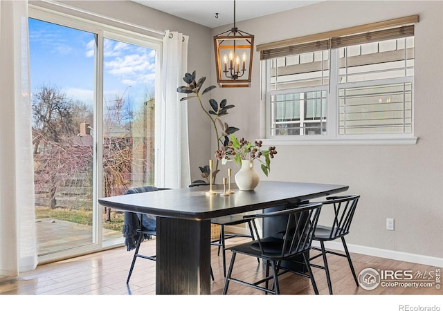 dining room featuring a wealth of natural light, baseboards, light wood-style floors, and an inviting chandelier