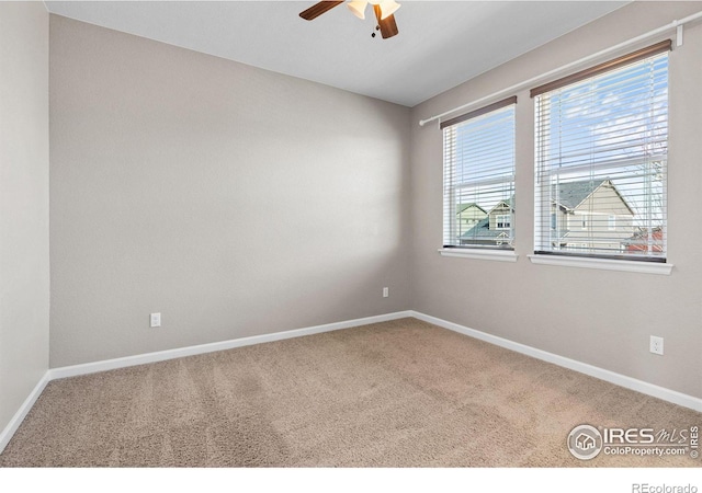 carpeted empty room featuring a ceiling fan and baseboards