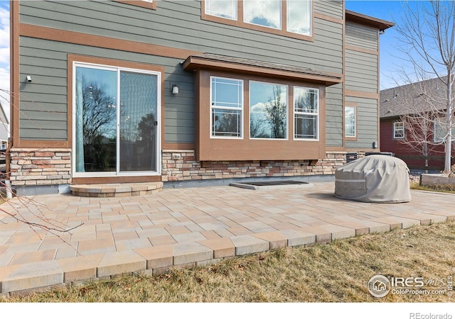 rear view of property featuring a patio area and stone siding