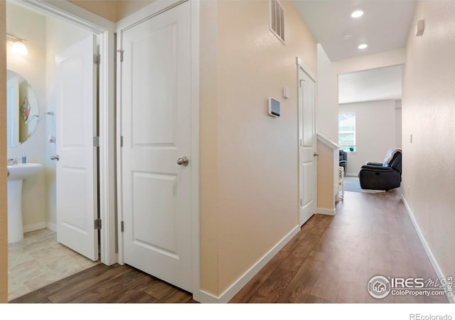 hall with visible vents, baseboards, and wood finished floors