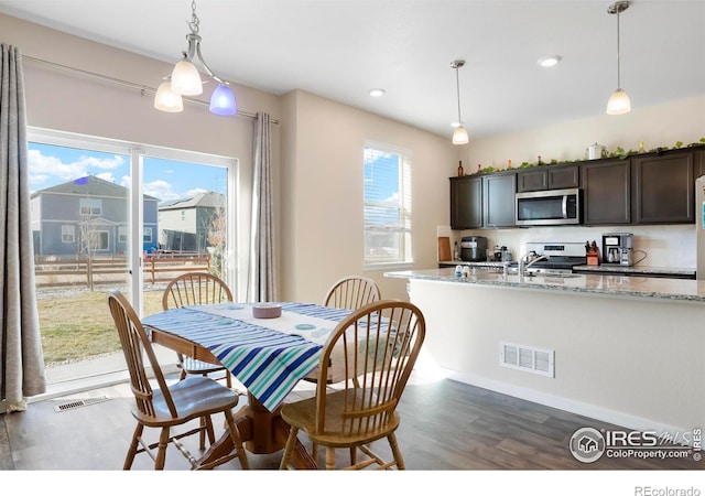 dining room with visible vents, a healthy amount of sunlight, and wood finished floors