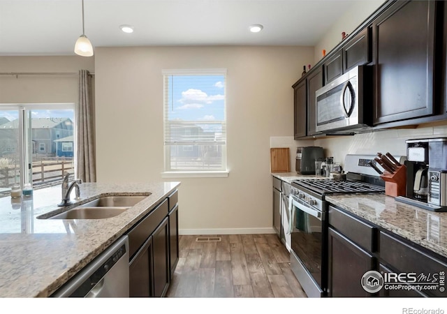 kitchen with visible vents, light wood-style flooring, a sink, stainless steel appliances, and dark brown cabinetry