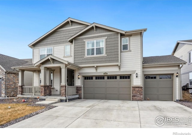 craftsman inspired home with a porch, stone siding, and driveway