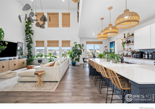 kitchen with a breakfast bar, a sink, wood finished floors, open floor plan, and white cabinets