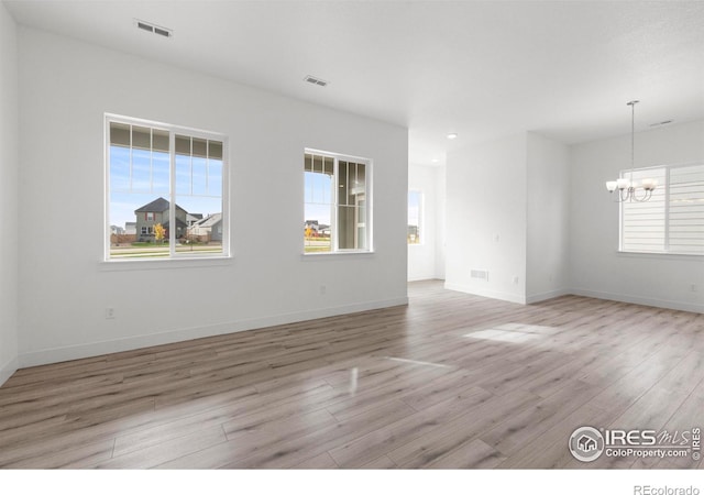 unfurnished room with a notable chandelier, baseboards, visible vents, and light wood finished floors