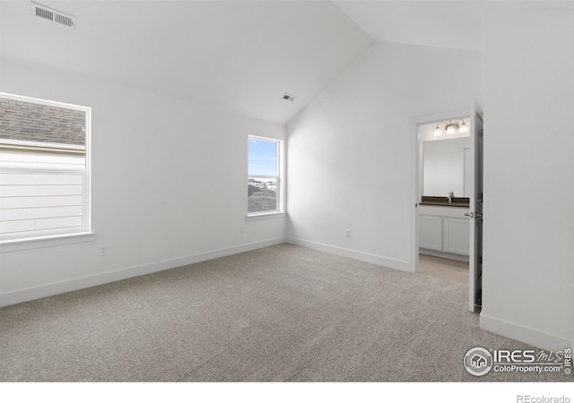 unfurnished room with vaulted ceiling, baseboards, visible vents, and light carpet