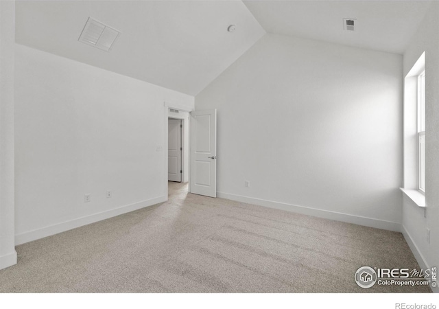 spare room featuring vaulted ceiling, visible vents, baseboards, and carpet floors