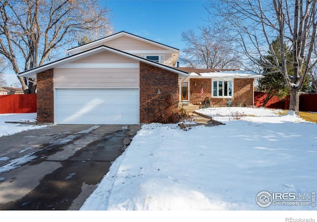 view of front of home with a garage, brick siding, driveway, and fence