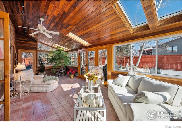 sunroom / solarium featuring a ceiling fan, vaulted ceiling with skylight, rail lighting, and wood ceiling