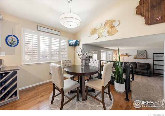 dining room featuring baseboards, baseboard heating, lofted ceiling, and wood finished floors