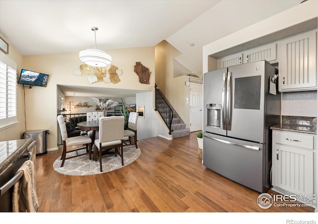 kitchen with pendant lighting, light wood-type flooring, lofted ceiling, and stainless steel fridge with ice dispenser