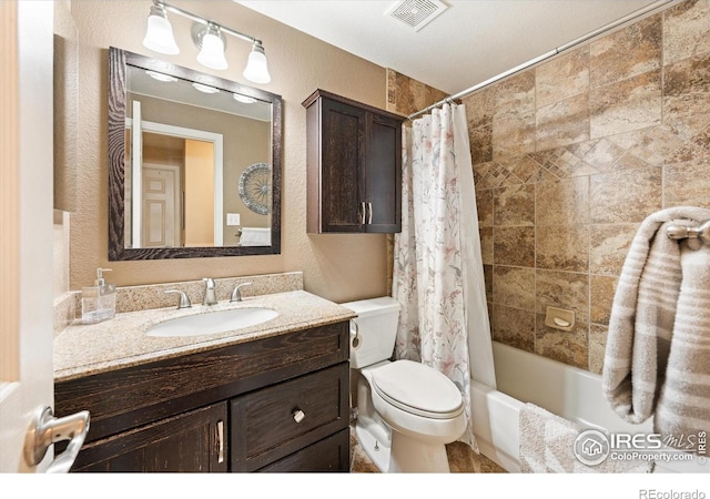 full bath with vanity, toilet, a textured wall, and visible vents