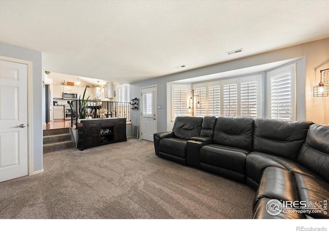 living area featuring visible vents, light colored carpet, and a textured ceiling