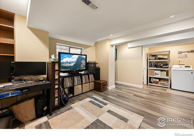 living room with light wood-type flooring, visible vents, washer / dryer, and built in features