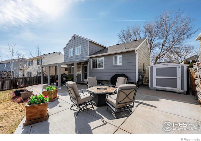 rear view of property with a patio, a fenced backyard, an outdoor structure, a fire pit, and a storage shed