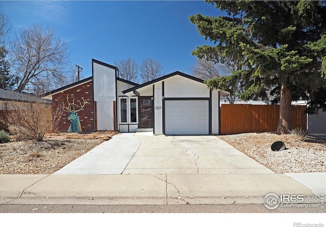 mid-century modern home featuring concrete driveway, an attached garage, and fence