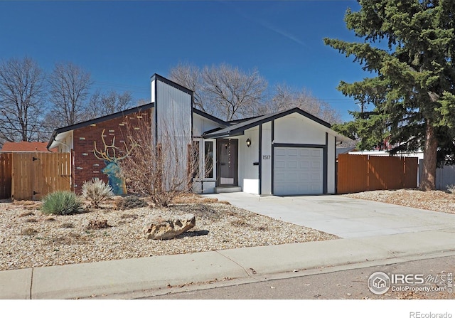 view of front facade featuring concrete driveway, an attached garage, and fence