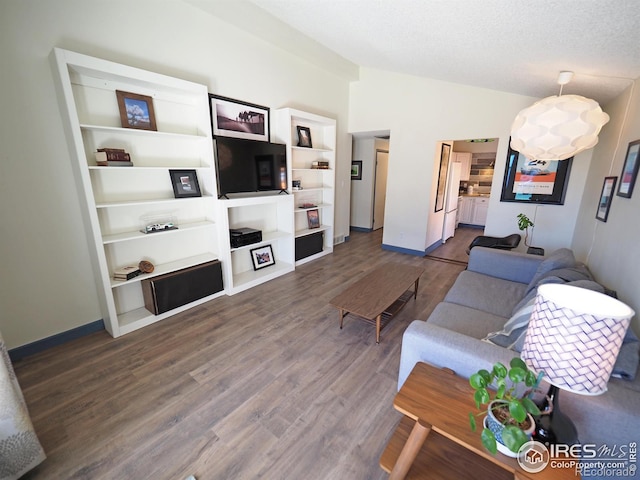 living area with lofted ceiling, baseboards, dark wood-type flooring, and a textured ceiling