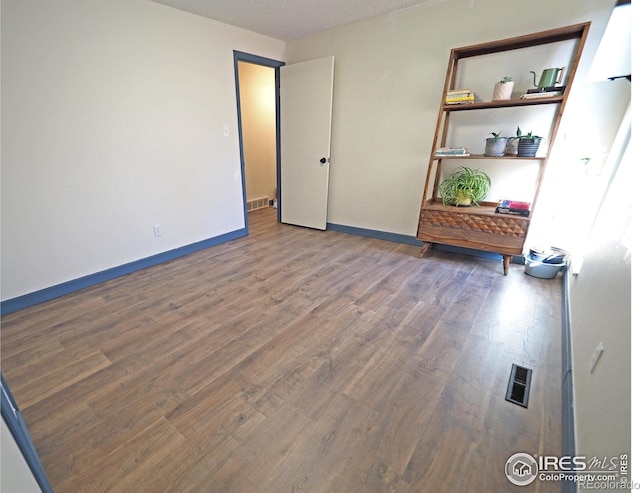 unfurnished bedroom with wood finished floors, visible vents, and baseboards