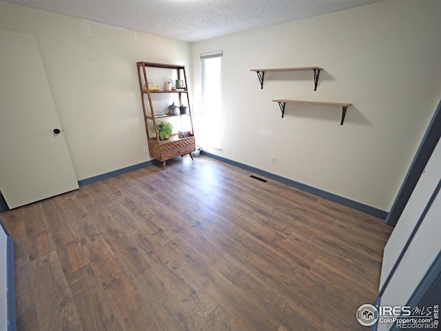 unfurnished bedroom featuring visible vents, a textured ceiling, baseboards, and wood finished floors