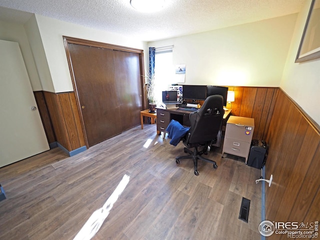 office with wood finished floors, a wainscoted wall, wood walls, and a textured ceiling