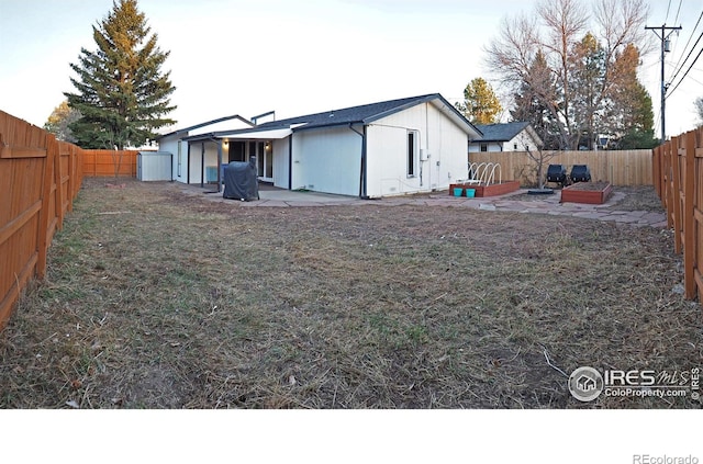 rear view of property featuring a patio area, a lawn, and a fenced backyard