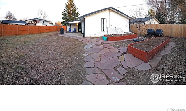 view of yard with a fenced backyard, a patio, and a vegetable garden