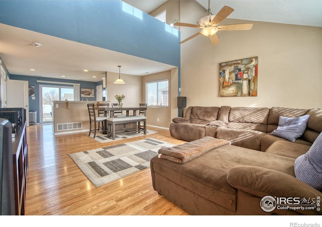 living room featuring light wood-type flooring, visible vents, baseboards, and ceiling fan