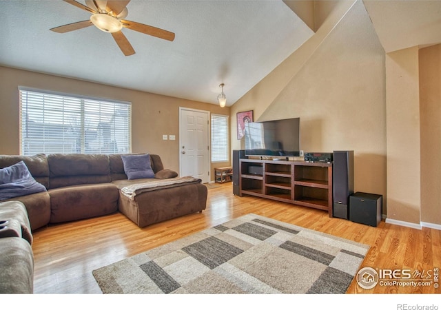 living area with lofted ceiling, wood finished floors, a ceiling fan, and baseboards