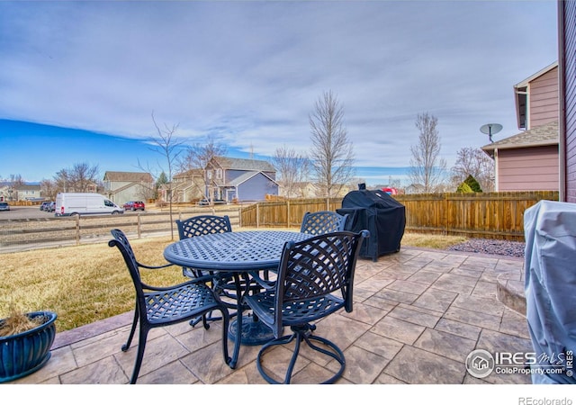 view of patio with outdoor dining area, a fenced backyard, and a grill