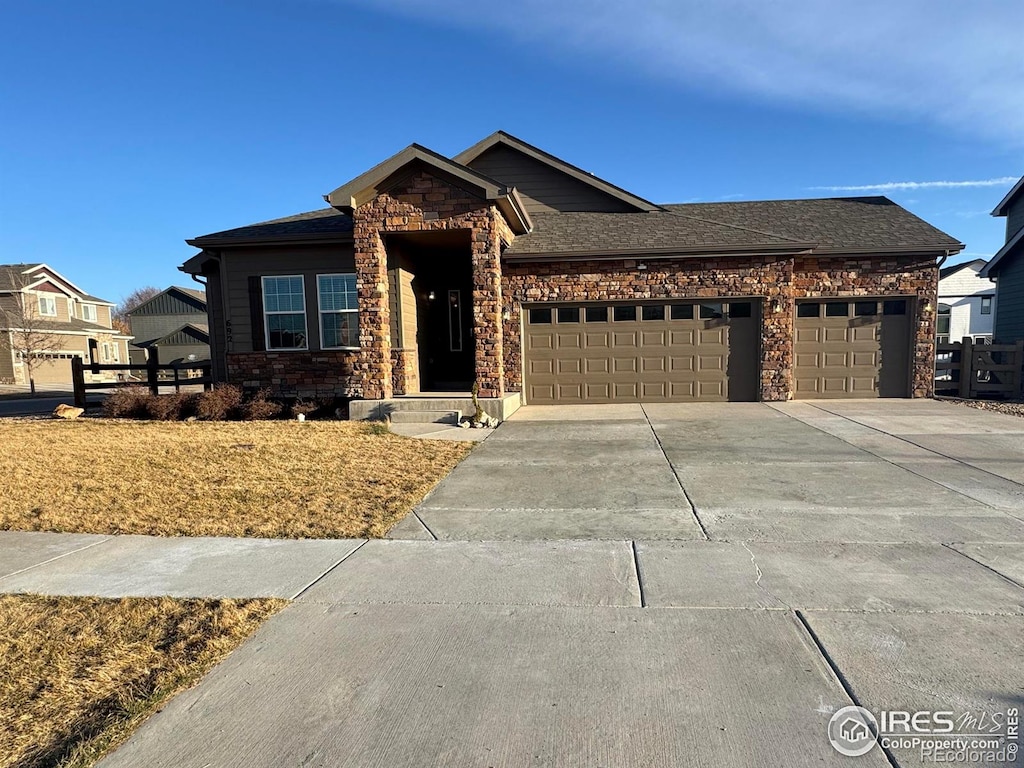 view of front of property with a garage, stone siding, roof with shingles, and concrete driveway