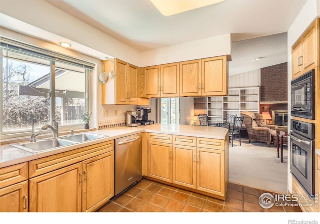 kitchen with dark tile patterned floors, light countertops, appliances with stainless steel finishes, a peninsula, and a sink