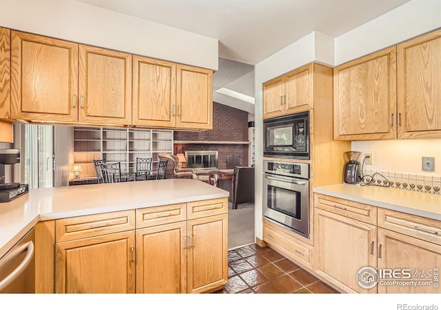 kitchen with appliances with stainless steel finishes, dark tile patterned floors, light brown cabinetry, and light countertops