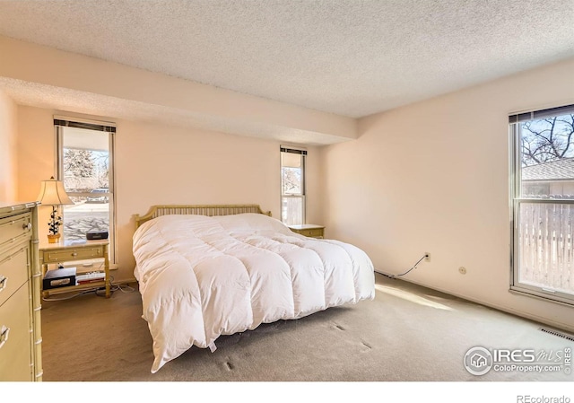 carpeted bedroom featuring multiple windows, visible vents, and a textured ceiling