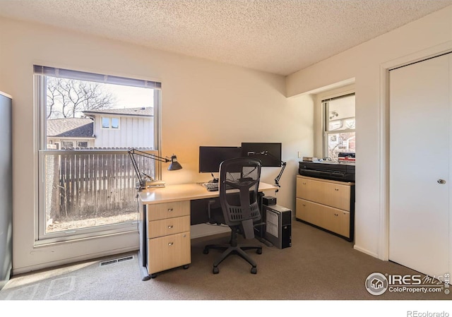 carpeted office featuring visible vents and a textured ceiling