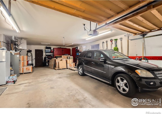 garage featuring freestanding refrigerator and a garage door opener