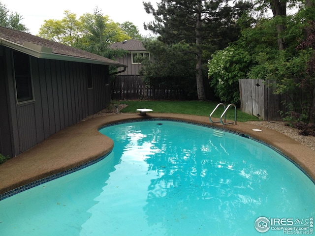 view of swimming pool featuring a fenced in pool, a diving board, and fence