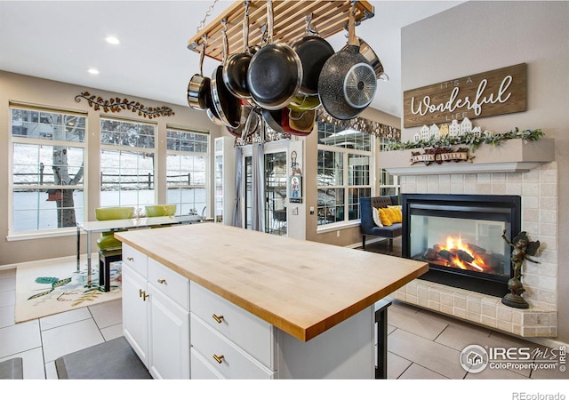 2073 River W Dr, Windsor, CO 80550 - kitchen featuring wooden counters, light tile patterned floors, a tiled fireplace, white cabinets, and recessed lighting