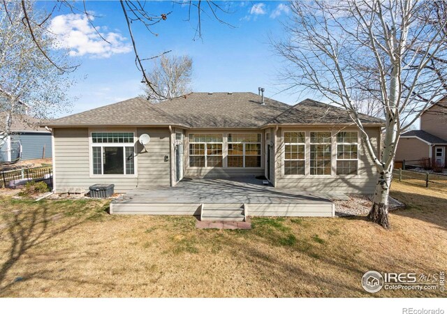 2073 River W Dr, Windsor, CO 80550 - back of property featuring fence, a lawn, a shingled roof, and a deck